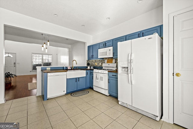 kitchen with blue cabinets, white appliances, dark countertops, and light tile patterned flooring