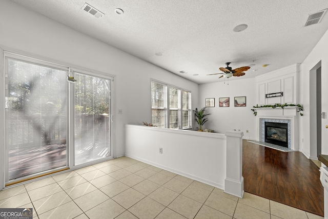 interior space with a fireplace with flush hearth, visible vents, ceiling fan, and light tile patterned flooring