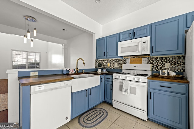 kitchen featuring white appliances, butcher block counters, blue cabinetry, and a sink