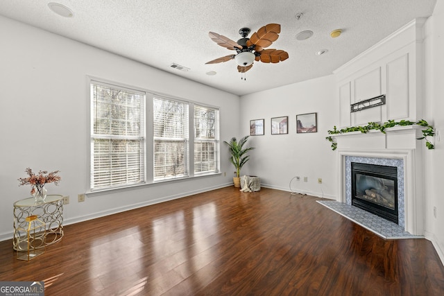 living area with dark wood finished floors, a fireplace, visible vents, a ceiling fan, and a textured ceiling