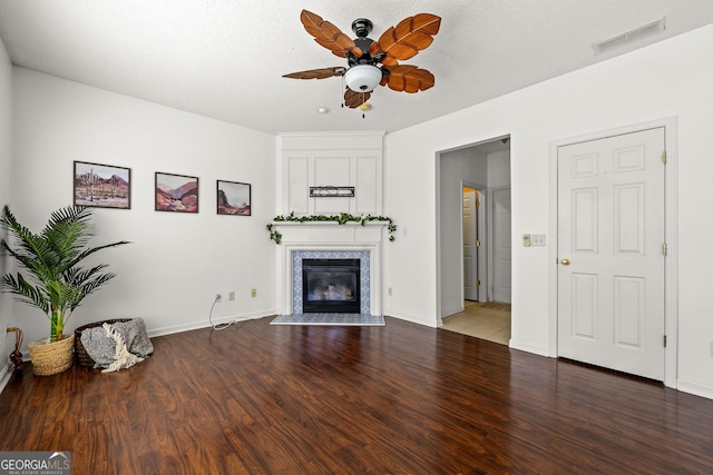 unfurnished living room with visible vents, a ceiling fan, a glass covered fireplace, wood finished floors, and baseboards