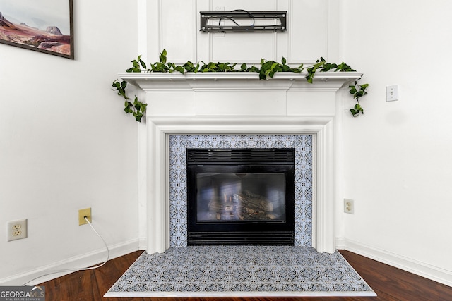 room details with a tile fireplace, baseboards, and wood finished floors