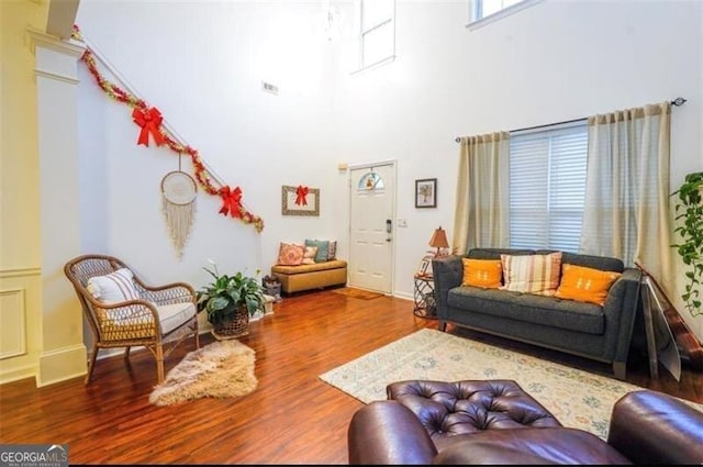 living room featuring decorative columns, wood-type flooring, and a high ceiling