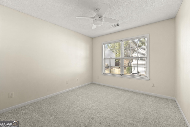 spare room featuring visible vents, baseboards, light colored carpet, ceiling fan, and a textured ceiling