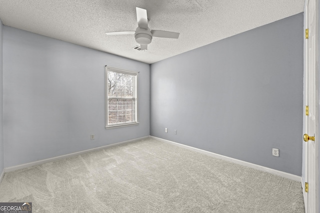 empty room with visible vents, baseboards, a ceiling fan, light colored carpet, and a textured ceiling