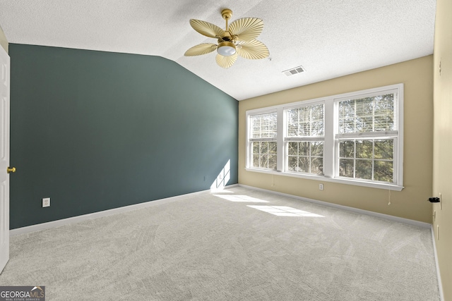 empty room with light colored carpet, lofted ceiling, visible vents, and baseboards