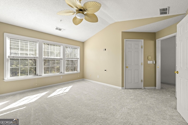 empty room featuring light carpet, baseboards, visible vents, and vaulted ceiling