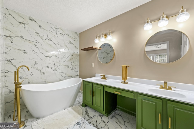 full bathroom featuring a textured ceiling, marble finish floor, a freestanding tub, and a sink