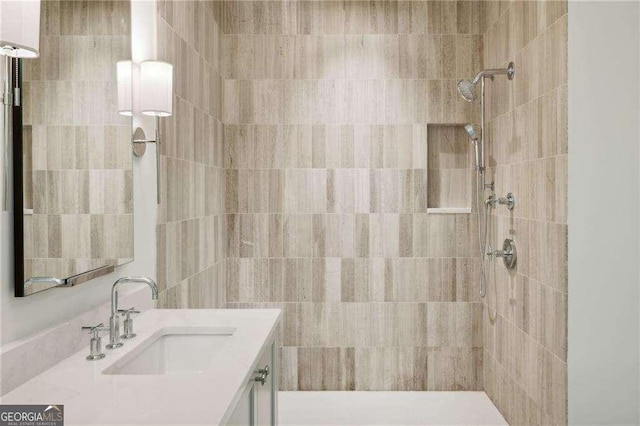 bathroom with tiled shower and vanity