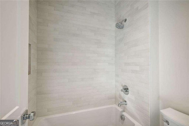 bathroom with toilet and tiled shower / bath combo