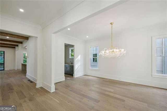 interior space featuring sink, an inviting chandelier, light wood-type flooring, ornamental molding, and beamed ceiling