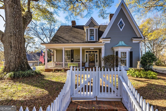 view of front of home featuring a porch, a chimney, and a fenced front yard