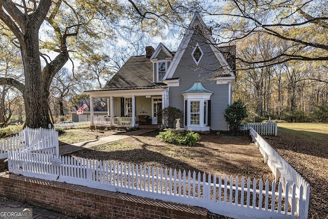 view of front of house featuring a porch, fence, and a chimney