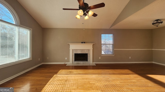 unfurnished living room featuring ceiling fan, lofted ceiling, a premium fireplace, and hardwood / wood-style floors