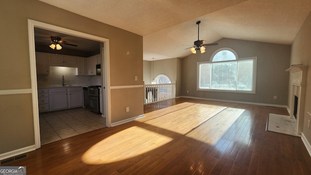 unfurnished living room featuring ceiling fan, lofted ceiling, sink, and light hardwood / wood-style flooring