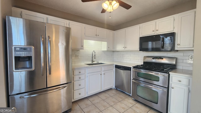 kitchen featuring appliances with stainless steel finishes, sink, white cabinets, decorative backsplash, and light tile patterned floors