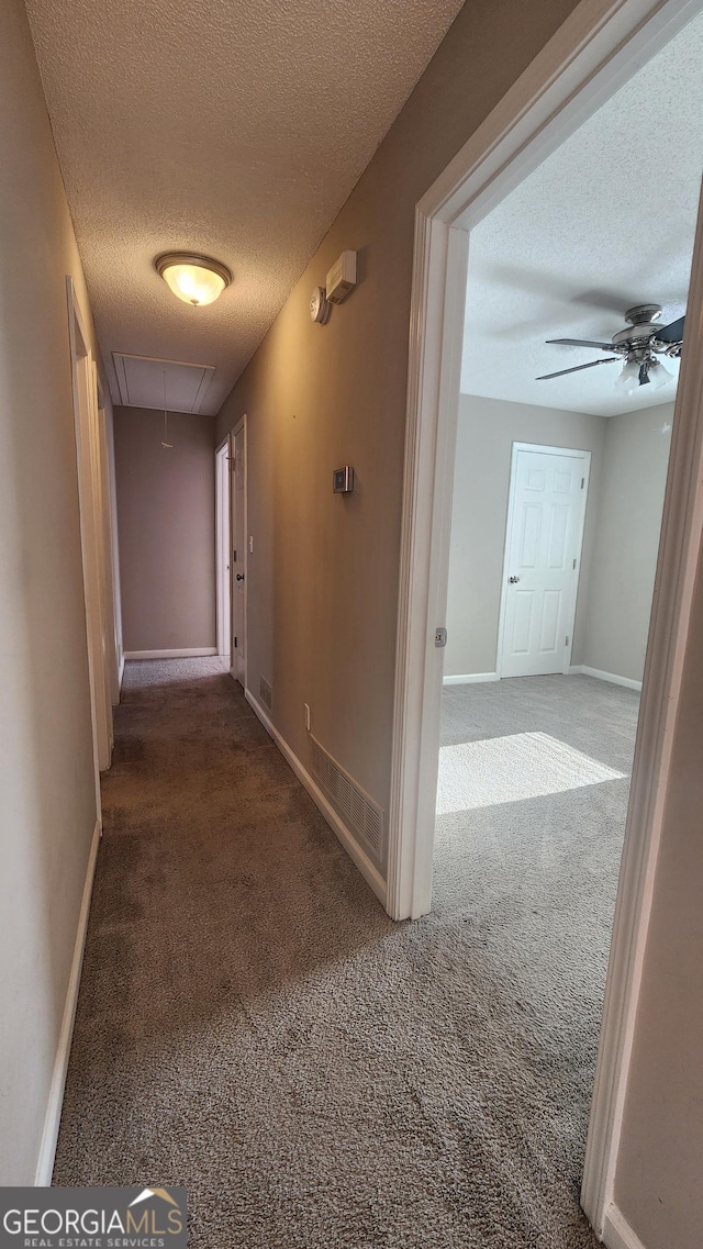 corridor featuring carpet flooring and a textured ceiling