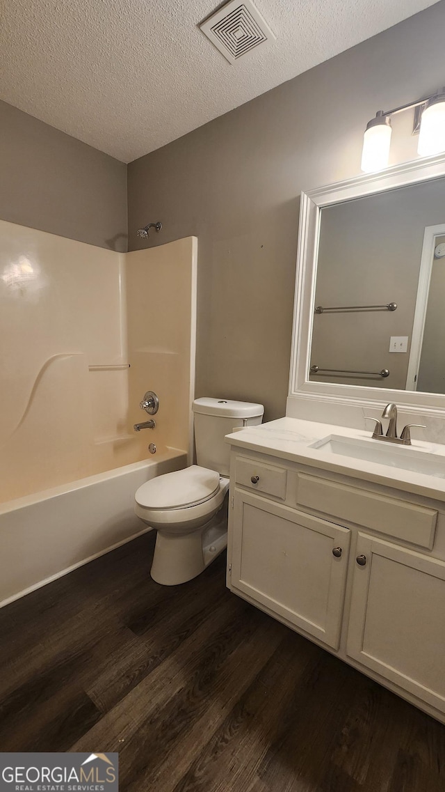 full bathroom with toilet, bathing tub / shower combination, a textured ceiling, vanity, and hardwood / wood-style floors