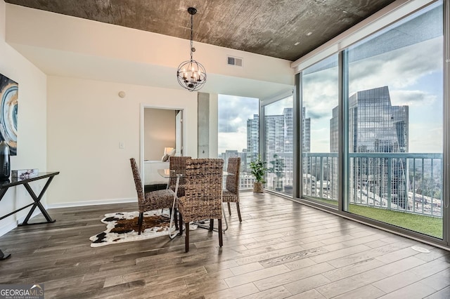 dining area featuring a notable chandelier, wood-type flooring, and a wall of windows