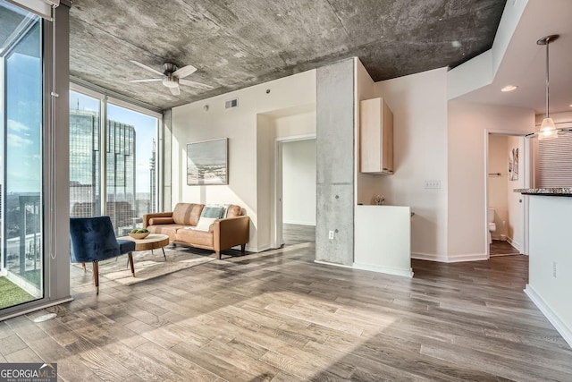 unfurnished living room featuring wood-type flooring, ceiling fan, and a wall of windows