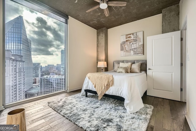 bedroom with expansive windows, wood-type flooring, and ceiling fan