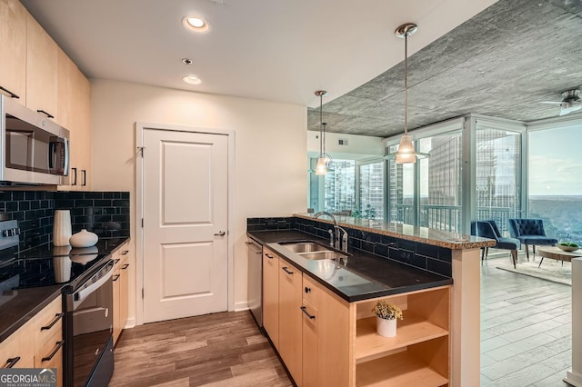 kitchen featuring stainless steel appliances, sink, hanging light fixtures, kitchen peninsula, and a healthy amount of sunlight