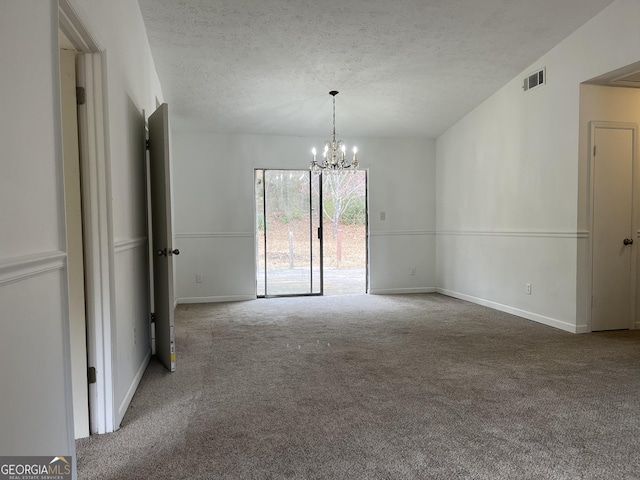 spare room featuring carpet floors, a textured ceiling, and a chandelier