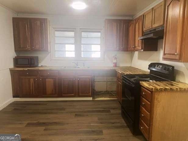 kitchen featuring black / electric stove, dark wood-type flooring, and sink