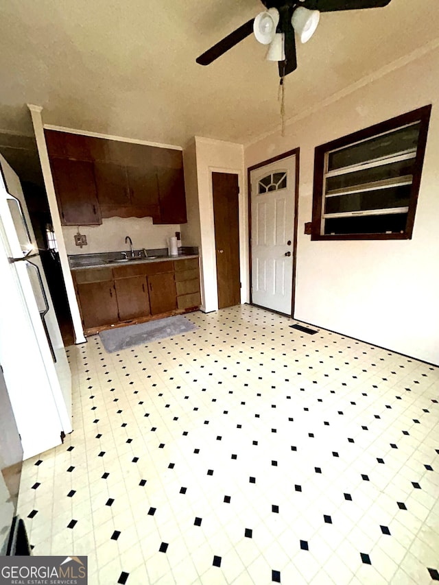 kitchen featuring white refrigerator, ornamental molding, sink, and ceiling fan