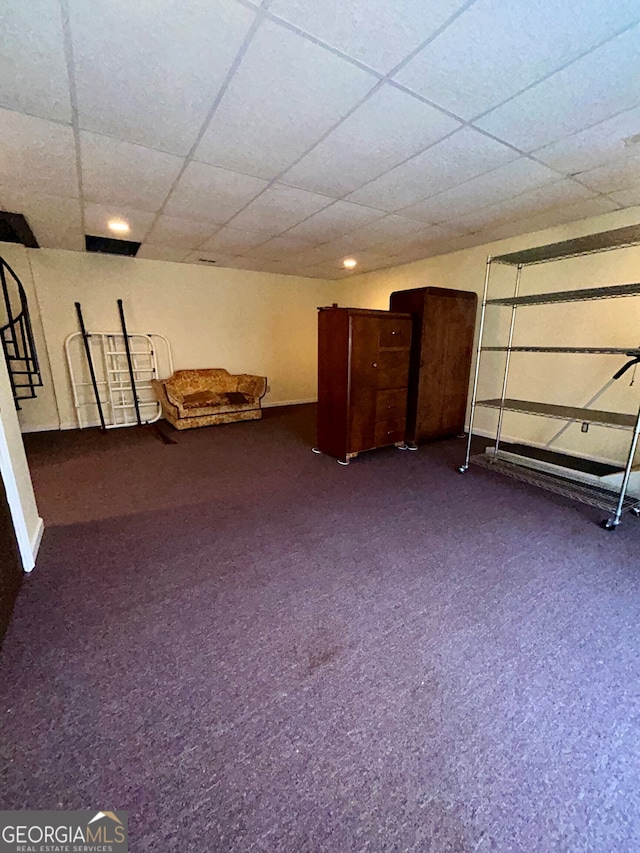 basement with dark carpet and a paneled ceiling