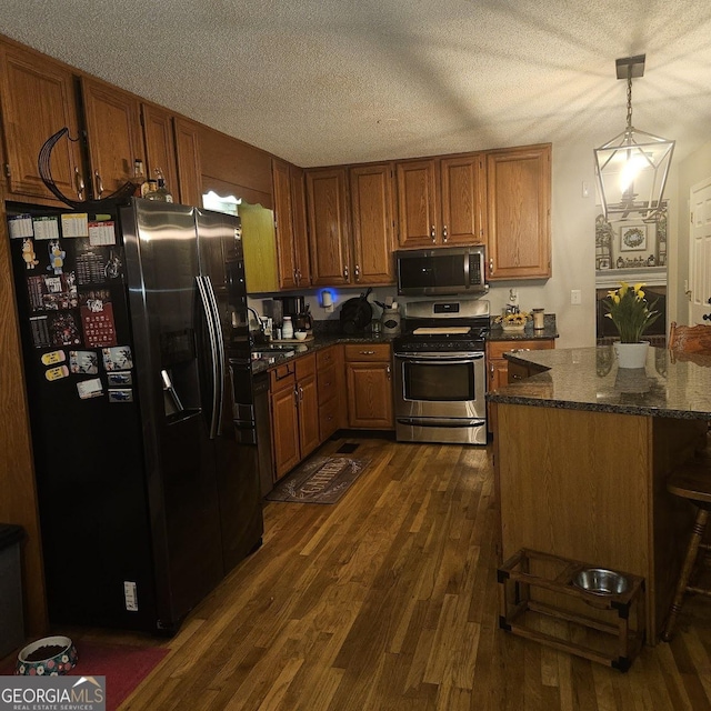 kitchen with pendant lighting, sink, stainless steel appliances, dark hardwood / wood-style floors, and a textured ceiling