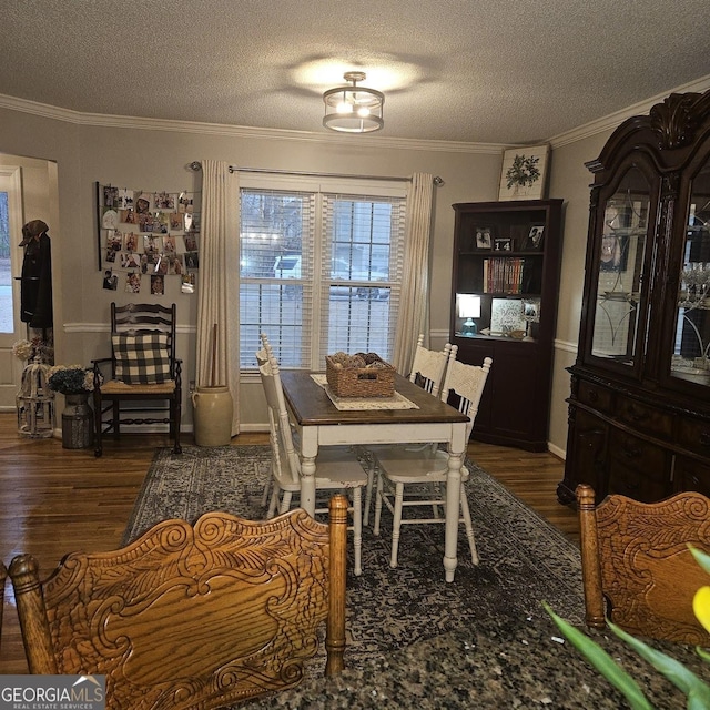 dining space featuring dark hardwood / wood-style flooring, ornamental molding, and a textured ceiling