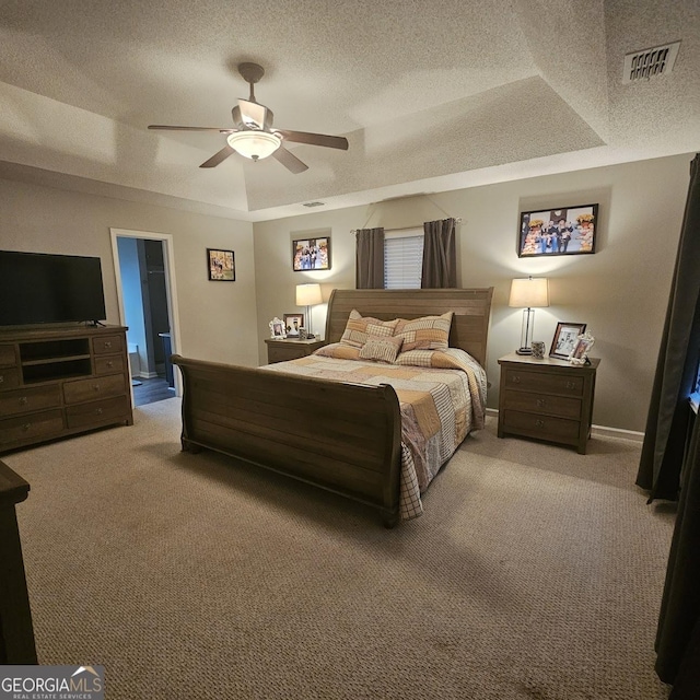 bedroom featuring a raised ceiling, ceiling fan, carpet flooring, and a textured ceiling