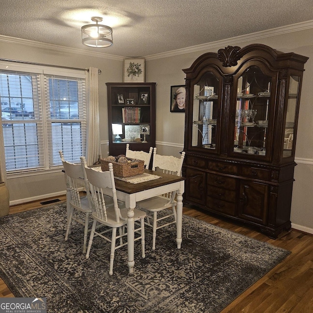 dining space with ornamental molding, dark wood-type flooring, and a textured ceiling