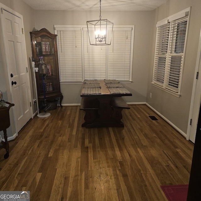 unfurnished dining area featuring a notable chandelier and dark hardwood / wood-style floors