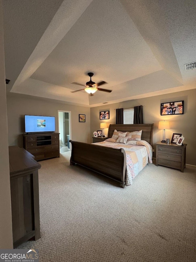 bedroom featuring ceiling fan, carpet, a textured ceiling, and a tray ceiling