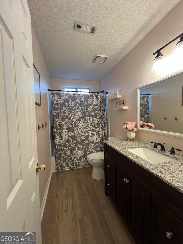 full bathroom featuring hardwood / wood-style flooring, vanity, toilet, shower / bathtub combination with curtain, and a textured ceiling