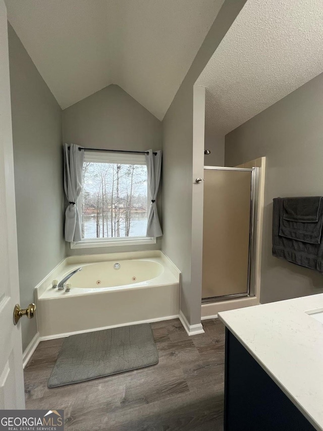 bathroom featuring wood-type flooring, vaulted ceiling, a textured ceiling, vanity, and independent shower and bath