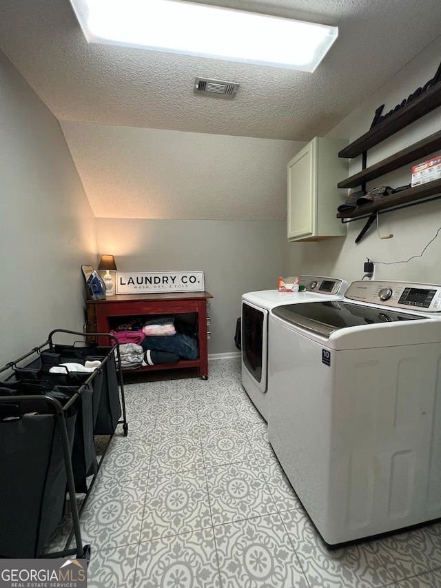 washroom featuring cabinets, washing machine and dryer, and a textured ceiling