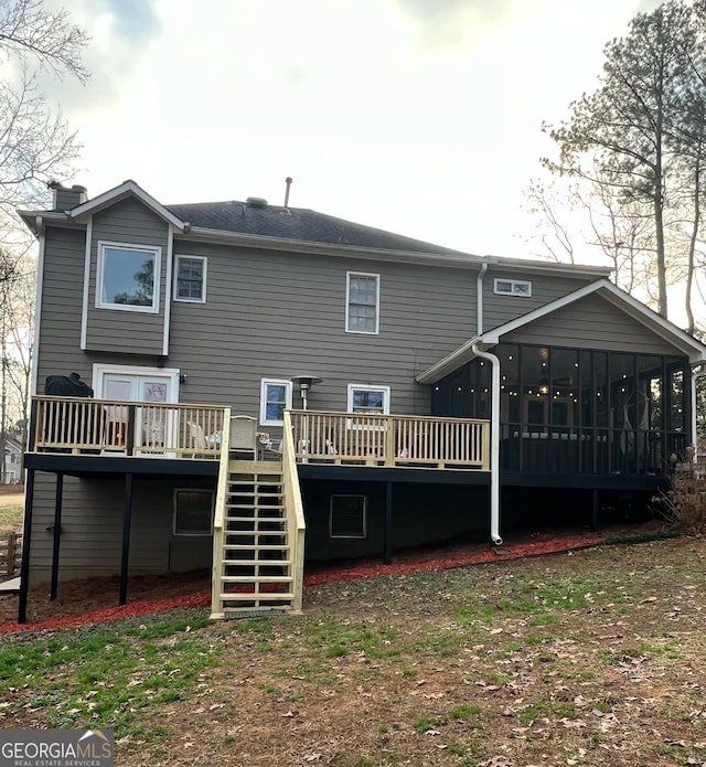 rear view of house featuring a sunroom and a deck