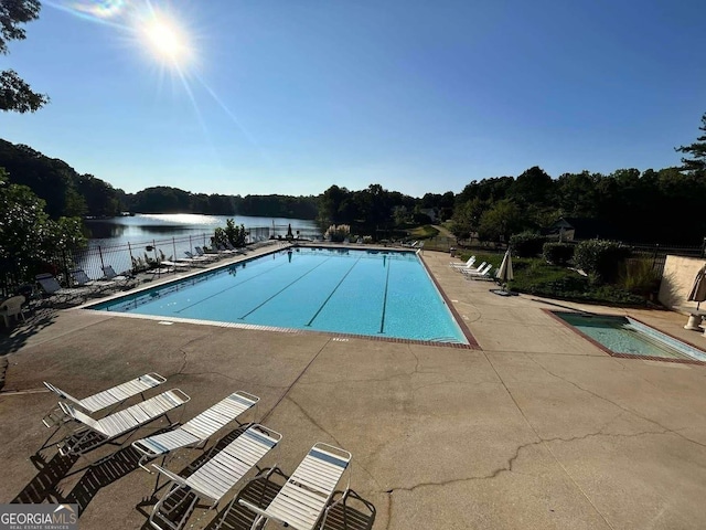 view of swimming pool featuring a patio and a water view