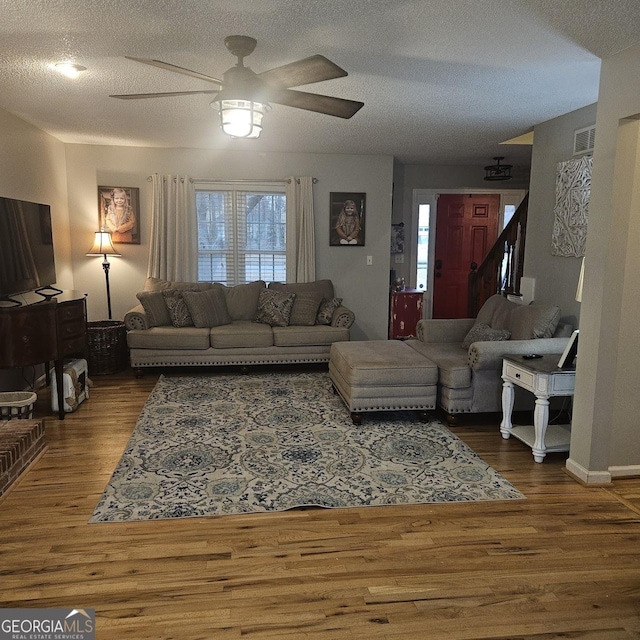 living room featuring ceiling fan, hardwood / wood-style floors, and a textured ceiling