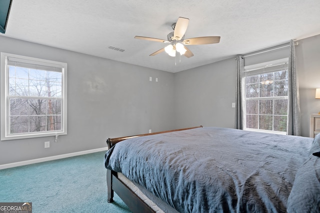 carpeted bedroom with ceiling fan and a textured ceiling