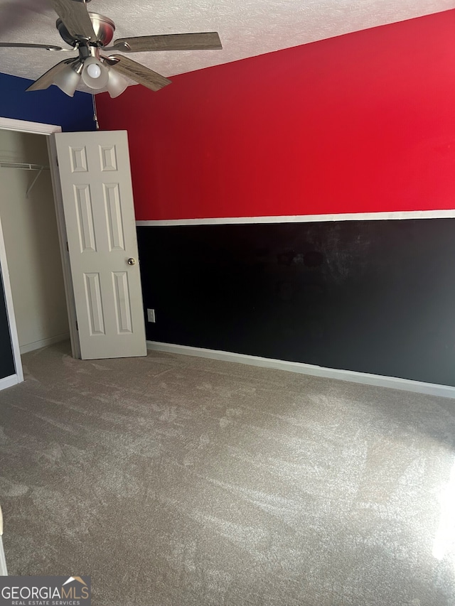 unfurnished bedroom featuring carpet, a textured ceiling, a closet, baseboards, and a ceiling fan