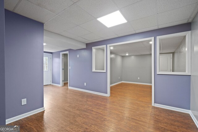unfurnished room featuring a drop ceiling, wood finished floors, and baseboards