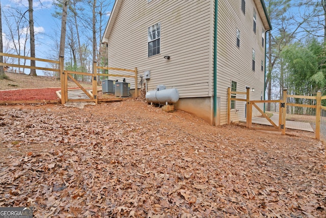 view of side of home featuring fence and central AC
