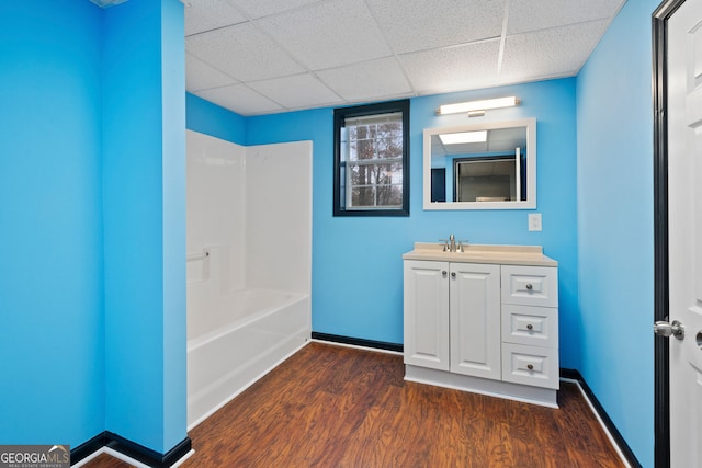 bathroom featuring wood finished floors, baseboards, vanity, and a paneled ceiling