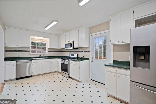 kitchen with stainless steel appliances, a sink, healthy amount of natural light, and dark countertops
