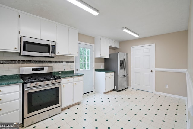 kitchen with appliances with stainless steel finishes, dark countertops, white cabinets, decorative backsplash, and baseboards
