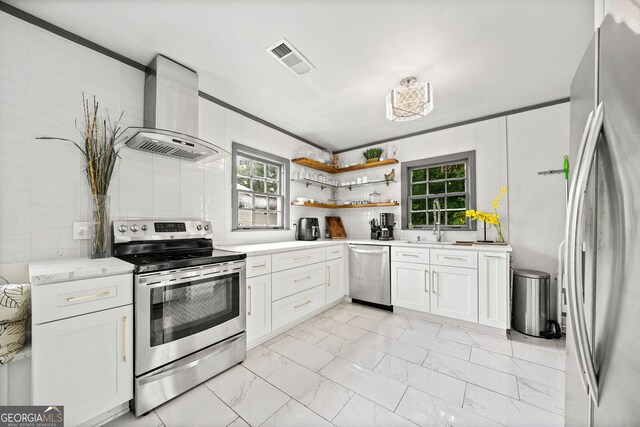 kitchen with wall chimney exhaust hood, white cabinetry, stainless steel appliances, and crown molding